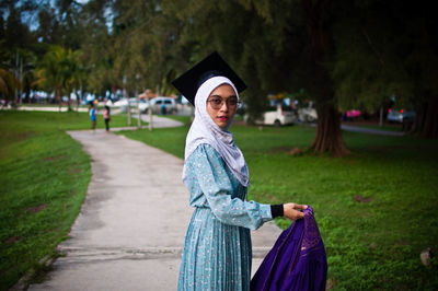 Portrait of smiling young woman standing by plants