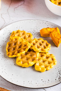 Homemade belgian pumpkin waffles on a plate on the table. autumn baking. closeup vertical view