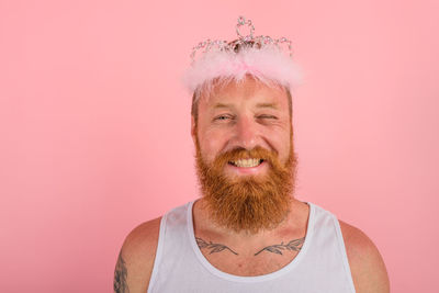 Portrait of young woman standing against pink background