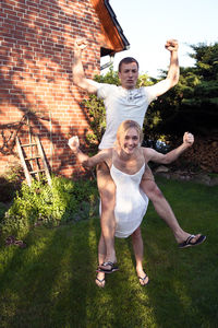 Portrait of smiling playful couple in yard against house