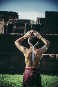 Man with arms raised standing in front of built structure