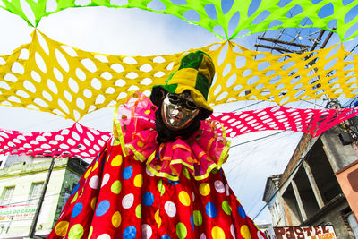 Person seated wearing carnival mask