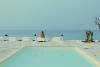 Rear view of people at swimming pool against clear sky