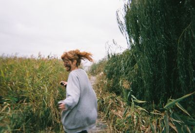 Side view of woman standing on field against sky