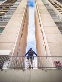 Low angle view of man standing by railing against buildings