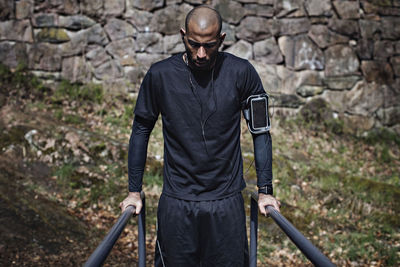 Mid adult male athlete exercising on parallel bars in forest