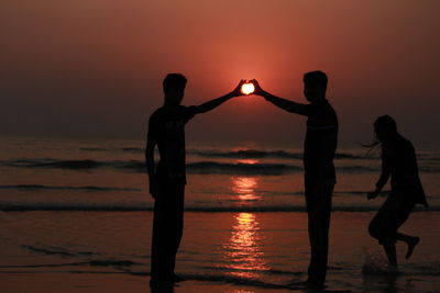 Silhouette people at beach during sunset