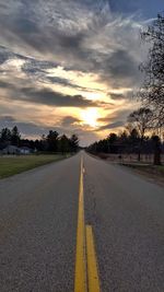 Surface level of empty road against sunset sky