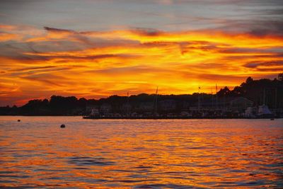 Scenic view of silhouette city against orange sky