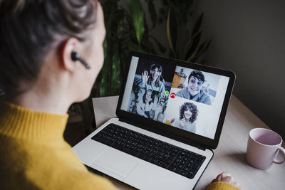 Young woman talking with friends over video conference on digital tablet while sitting at home