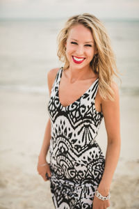 Portrait of cheerful young woman standing at beach