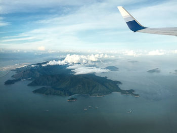 Aerial view of airplane flying over sea against sky