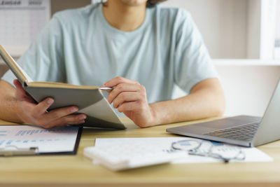 Midsection of woman using laptop at office