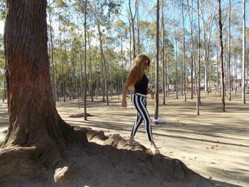 Side view of woman walking against trees in forest