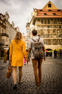 Rear view of people walking on street against buildings