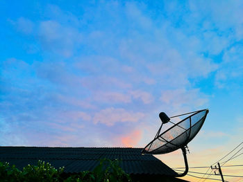 Low angle view of communications tower against cloudy sky