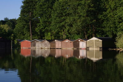 Houses by lake against trees