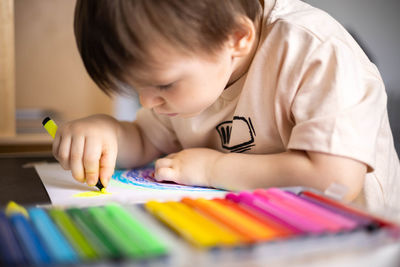 Close-up of boy drawing on book at home