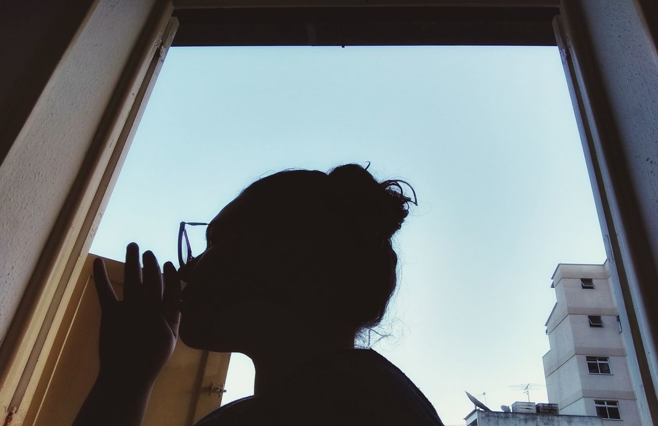 REAR VIEW OF WOMAN LOOKING AT WINDOW
