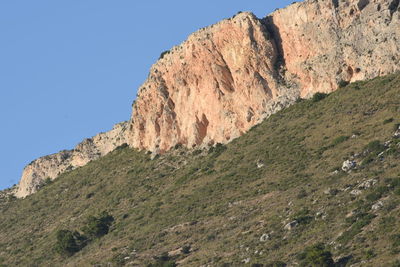 Low angle view of rocky mountains against clear sky