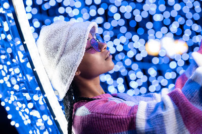 Joyful woman of color with a white beanie braided hairstyle and pink glasses enjoying the christmas