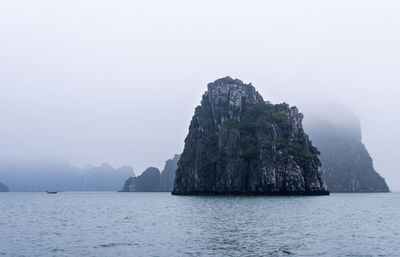 Rock formation in sea against sky