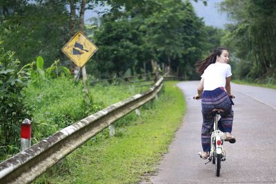 Rear view of woman riding bicycle on road