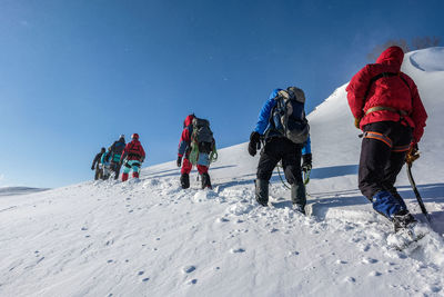 Low angle view of people on snow against clear sky