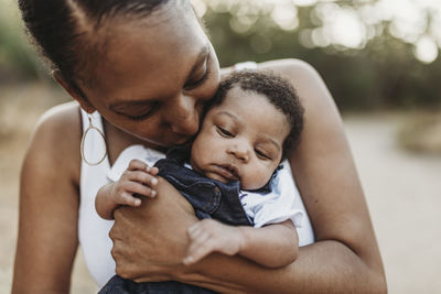 Close up portrait of young mother holdiing infant daughter outside