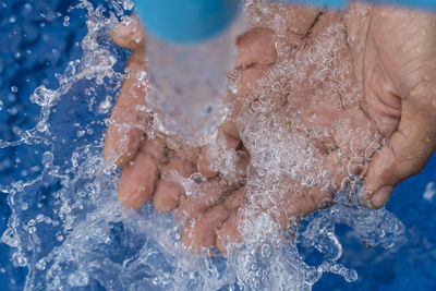 Close-up of hand holding water under pipe