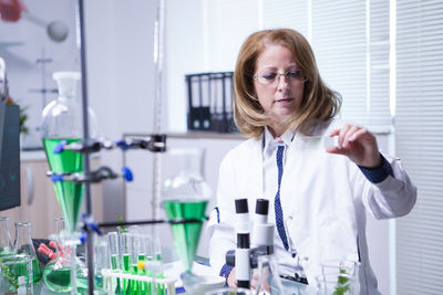 Portrait of female doctor holding medicine in laboratory