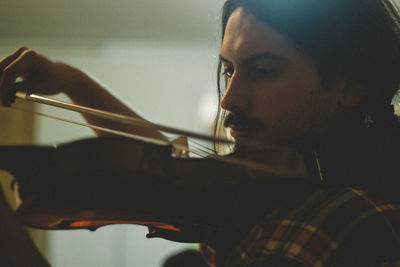 Close-up of young man playing violin at home