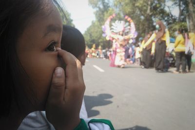 Side view of girl covering face with hand while standing on street