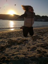 Full length of boy on beach against sky during sunset