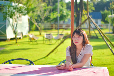 Young woman using mobile phone while sitting in park