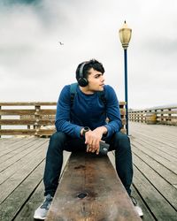 Full length of man sitting on pier against sky