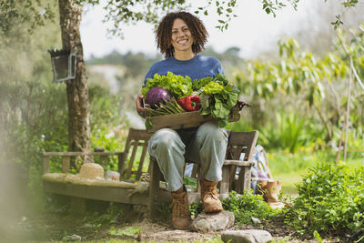 Portrait of smiling woman sitting by plants