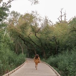  woman running on footpath amidst trees.