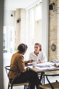 Smiling female architects discussing while working at home