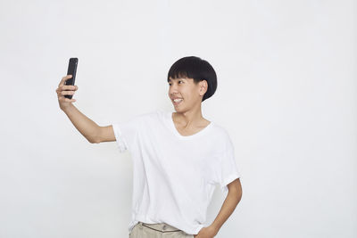 Man photographing with smart phone against white background