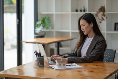 Young woman using phone while sitting on table