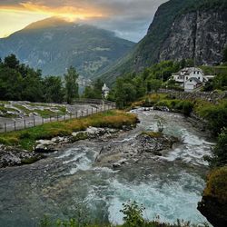 Scenic view of waterfall by mountains against sky