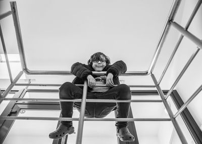 Low angle view of a kid hanging on the handrail of a staircase