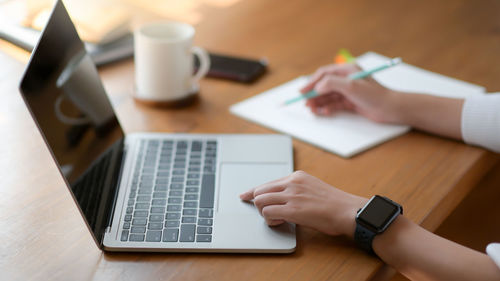 Midsection of man using mobile phone on table
