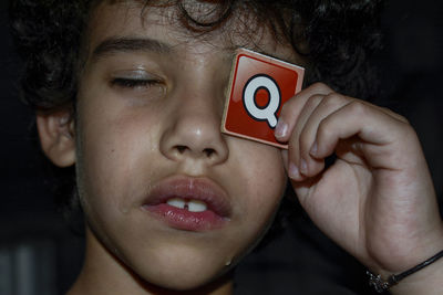 Close-up of boy crying while holding q sign