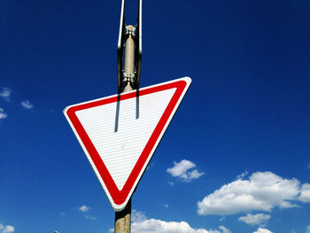 Low angle view of road sign against blue sky