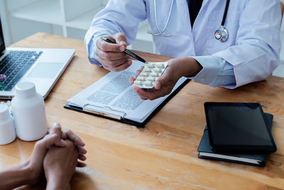 Midsection of man using smart phone on table