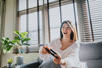 Young woman looking through mobile phone while sitting at home