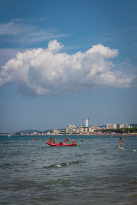 Nautical vessel on sea by buildings against sky