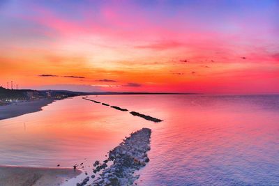 Scenic view of sea against dramatic sky during sunset